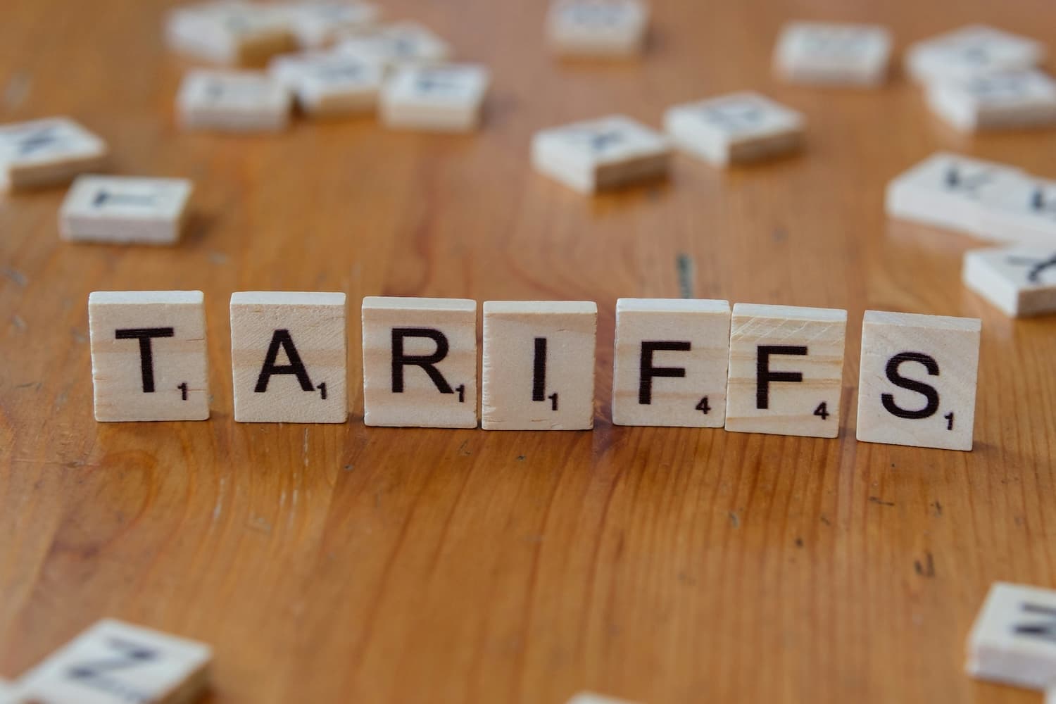 The word 'TARIFFS' spelled out with wooden letter tiles on a table, illustrating the topic of import duties.