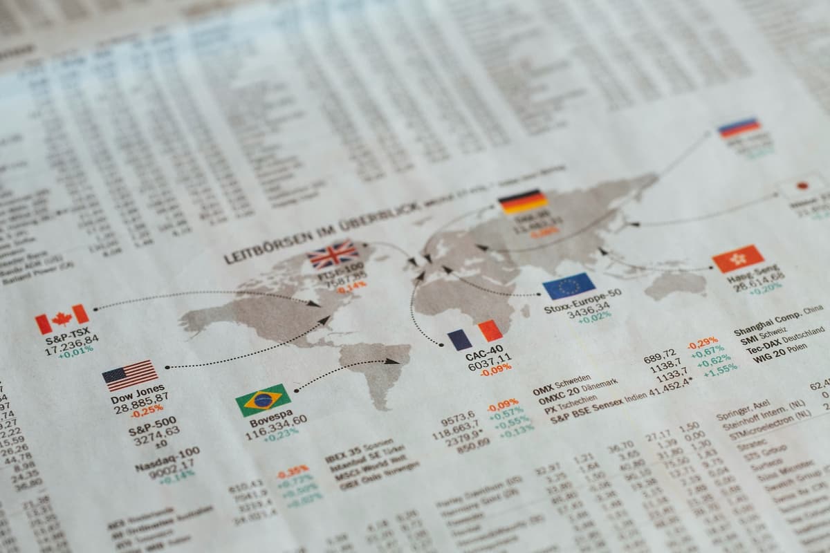 A financial newspaper showing global stock market data and a world map, representing the complexity of international landed cost.